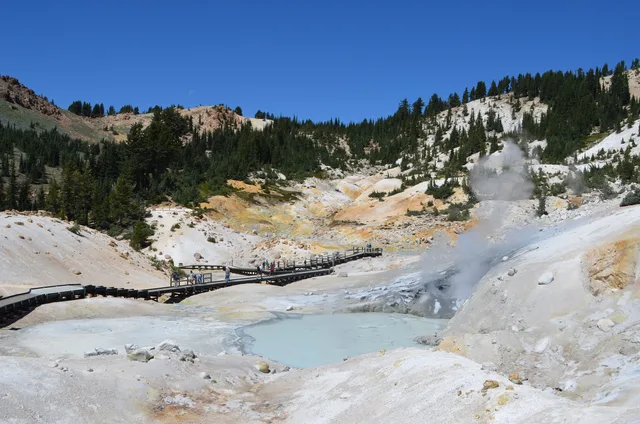 A boardwalk passes through a colorful, steaming hydrothermal basin.